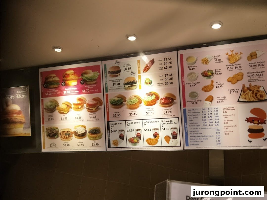 A brightly lit digital menu board displaying a variety of burgers, sides, and drinks at MOS Burger.