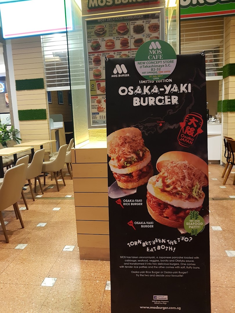 A promotional standee for MOS Burger's limited edition Osaka-Yaki Burger, with the shop interior in the background.