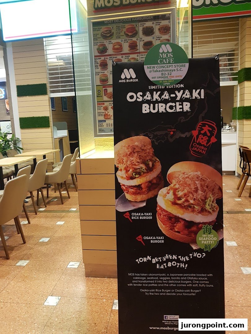 A promotional standee for MOS Burger's limited edition Osaka-Yaki Burger, with the shop interior in the background.