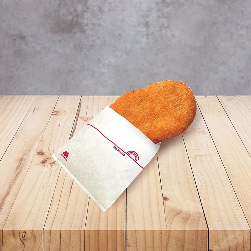 A golden-brown fried patty, likely a hash brown, partially wrapped in a MOS Burger paper sleeve.