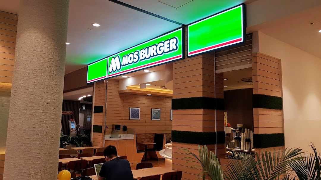 The illuminated entrance and interior seating area of a MOS Burger restaurant.