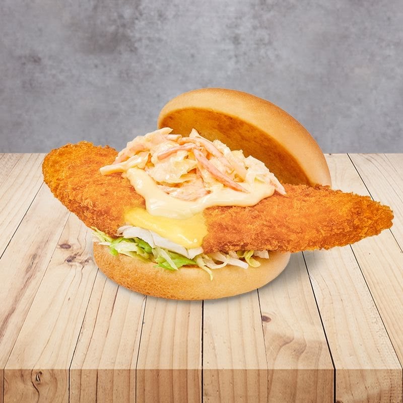 A close-up of a crispy fish burger with coleslaw and cheese on a wooden surface.
