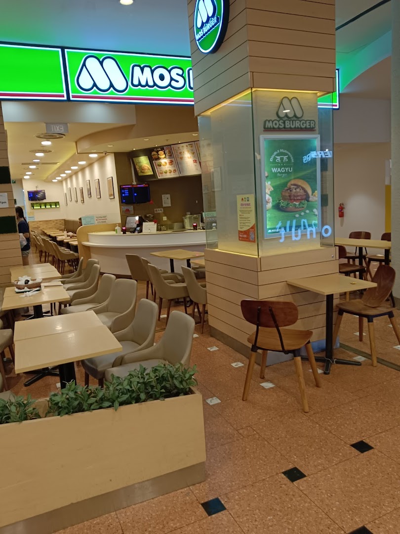 An inviting interior view of MOS Burger, showcasing comfortable seating, a service counter, and brand signage.