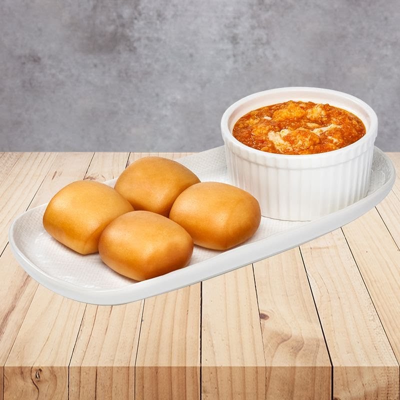 Four golden fried buns served with a rich, savory sauce in a white bowl on a wooden table.