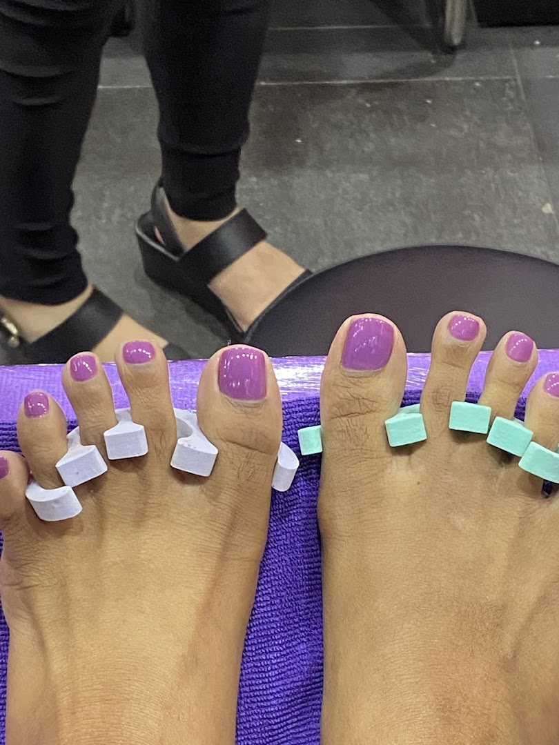 Close-up of feet with freshly painted purple toenails and toe separators during a pedicure.
