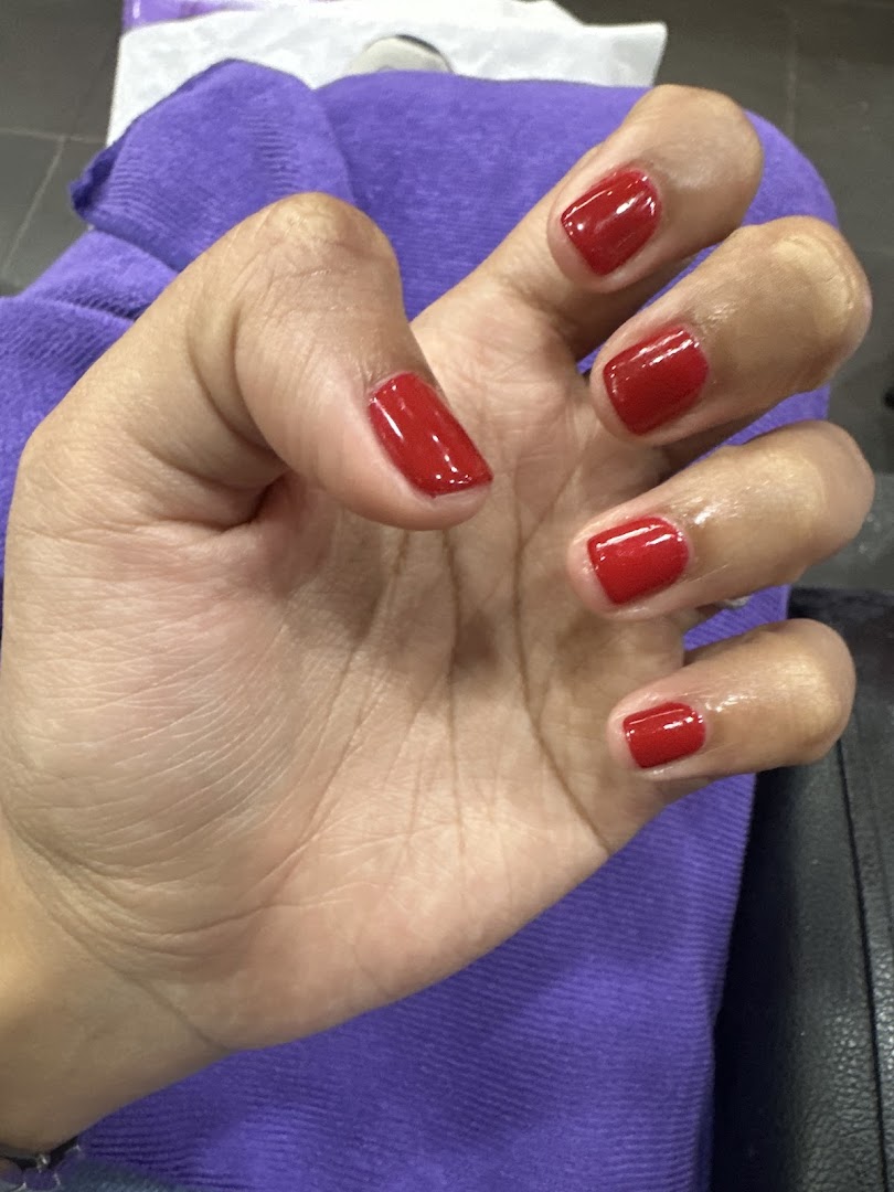 A hand showcasing freshly painted red nails, highlighting a service from Nail Palace.
