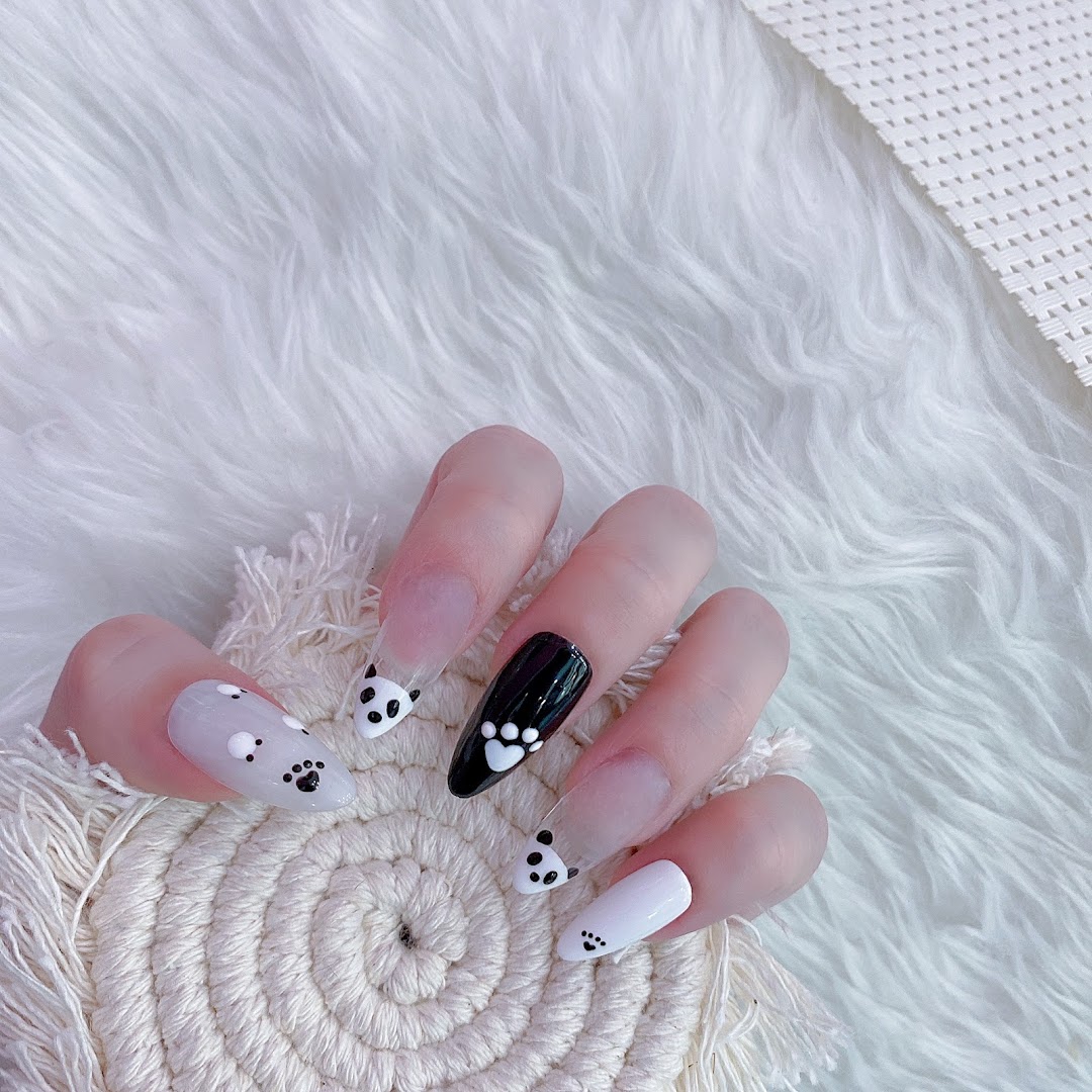 A hand displays long, clear and opaque nails adorned with cute panda faces and paw print designs.