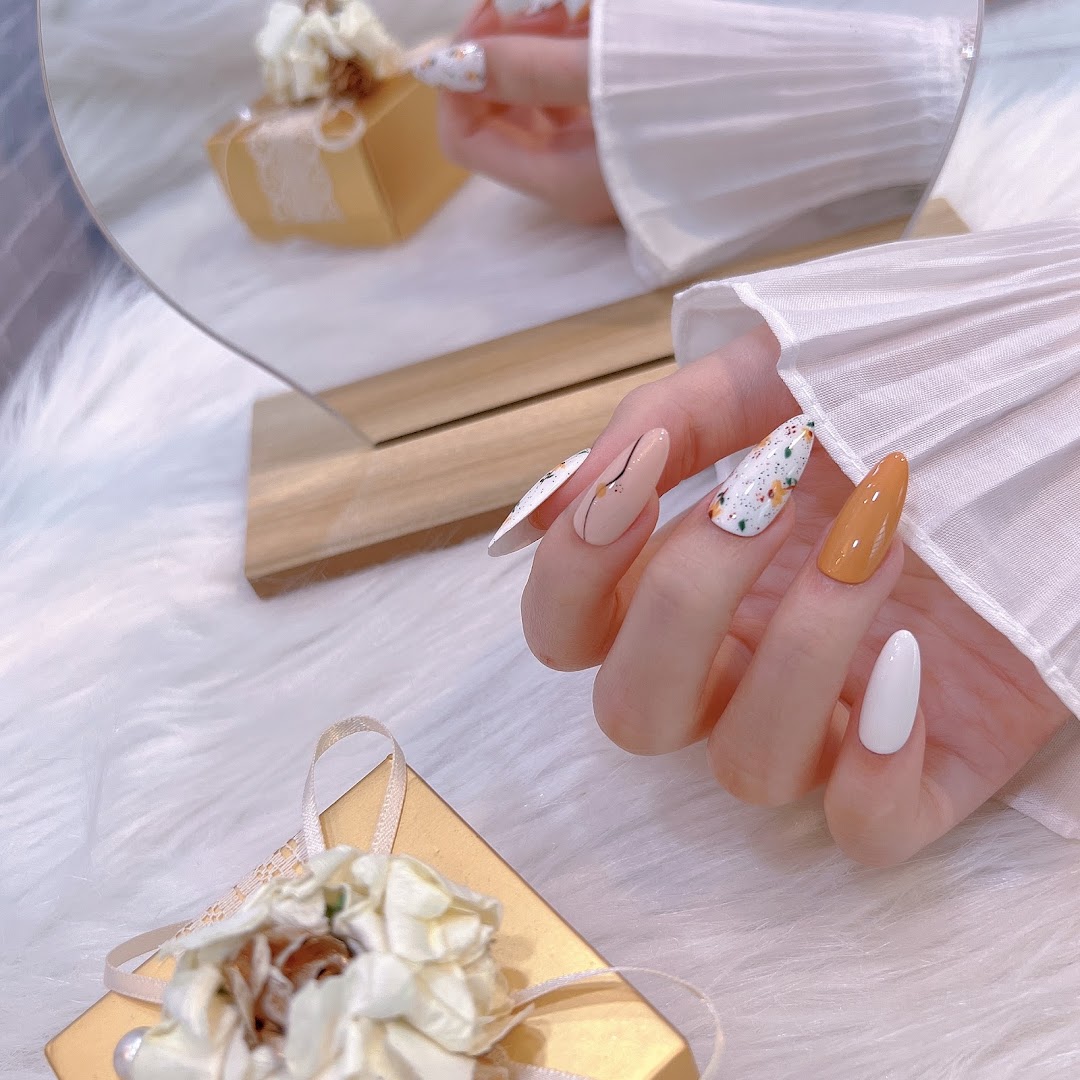 A hand displays beautifully manicured nails featuring diverse colors, patterns, and a sleek design.