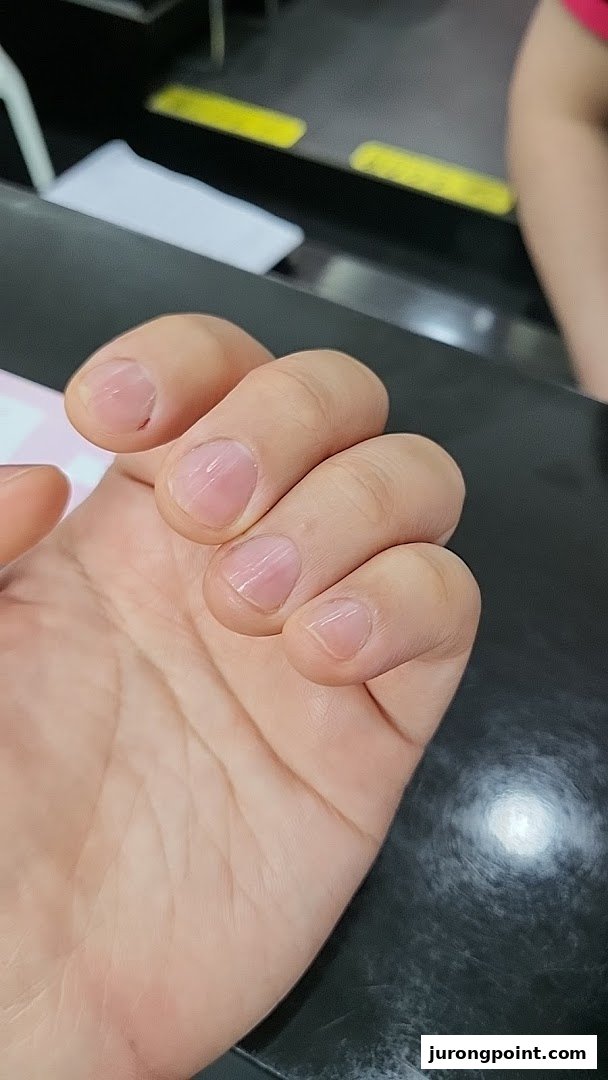 A close-up of a hand showcasing natural, unpolished fingernails, likely before or after a nail care service.