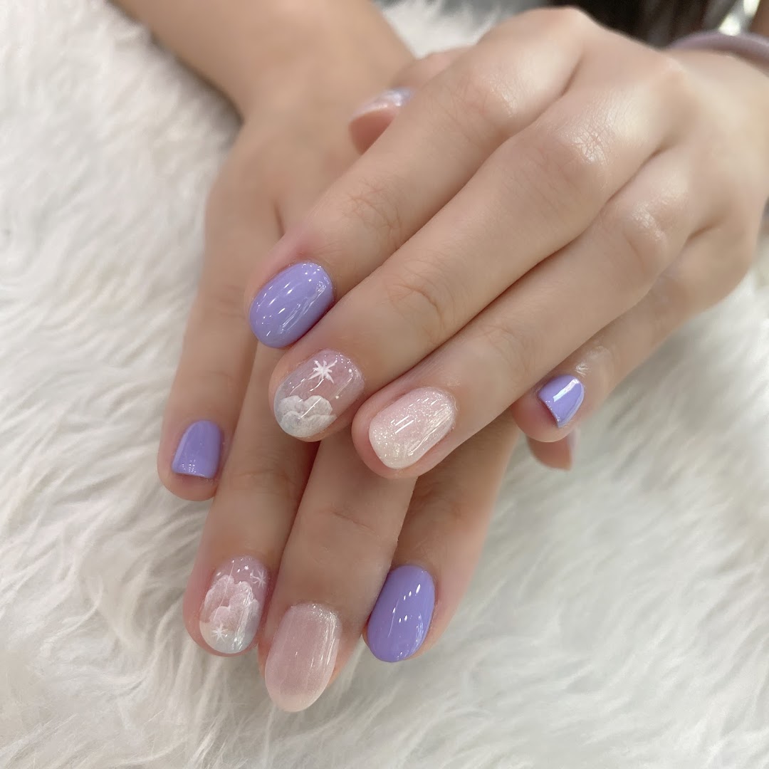 Close-up of hands showcasing a beautiful lavender and glitter nail design with cloud and star art.