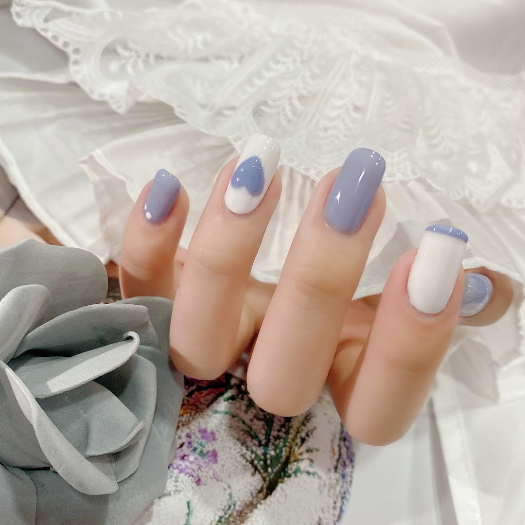 A hand showcasing a stylish manicure with lavender and white polish, featuring heart and French tip designs.