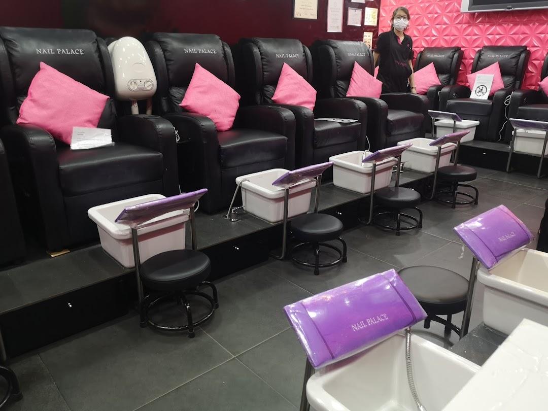 Interior view of Nail Palace showcasing comfortable pedicure stations and a staff member.