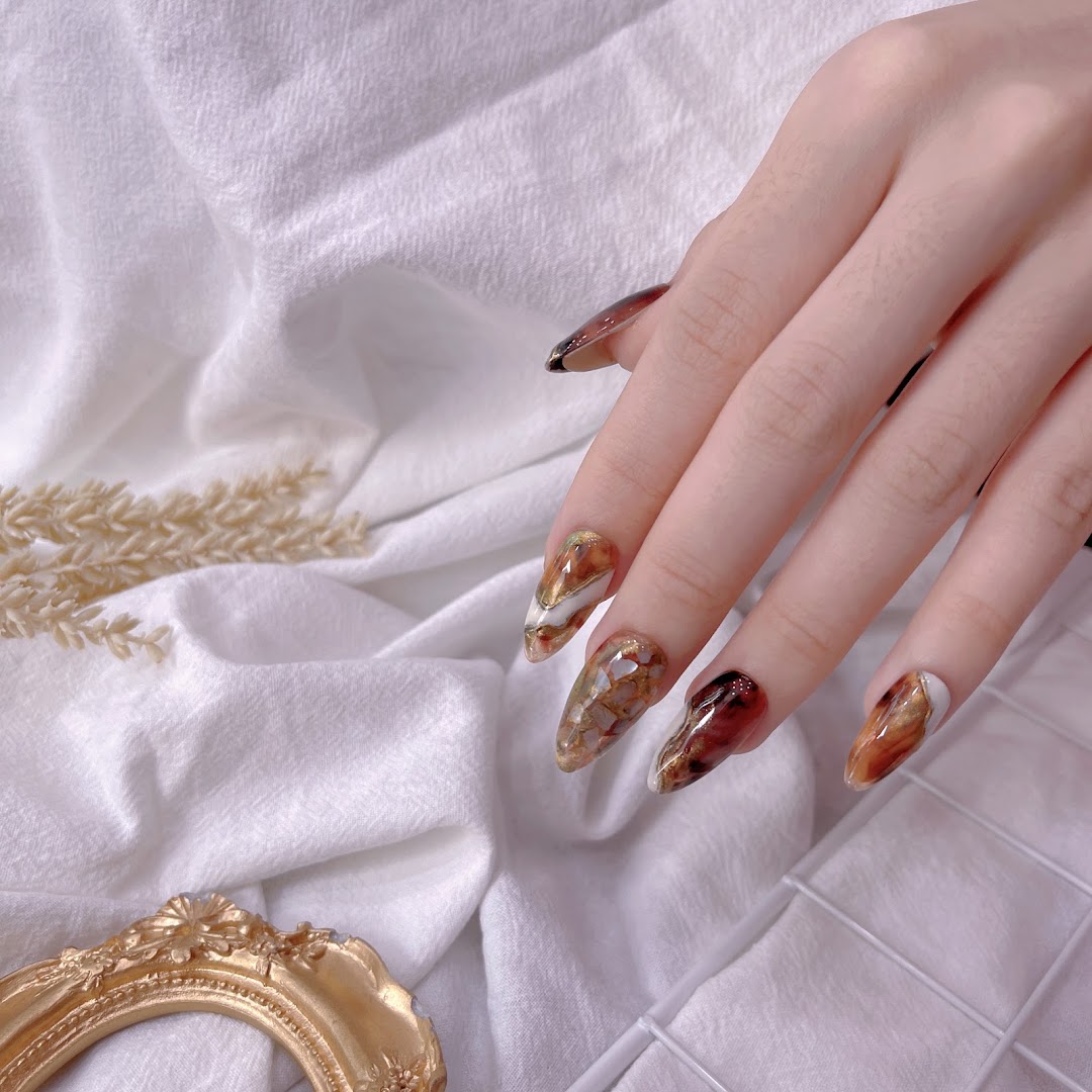 A hand showcasing long, intricately designed nails with a rich, marble-like pattern.