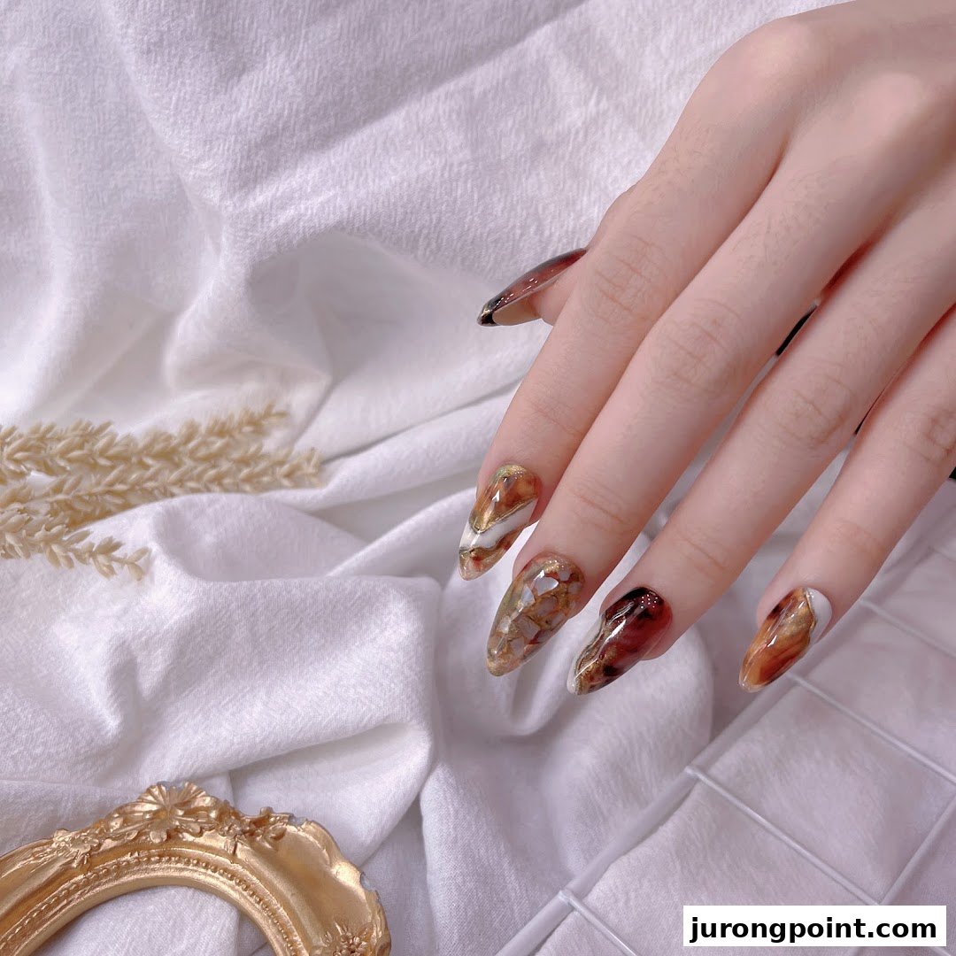 A hand showcasing long, intricately designed nails with a rich, marble-like pattern.