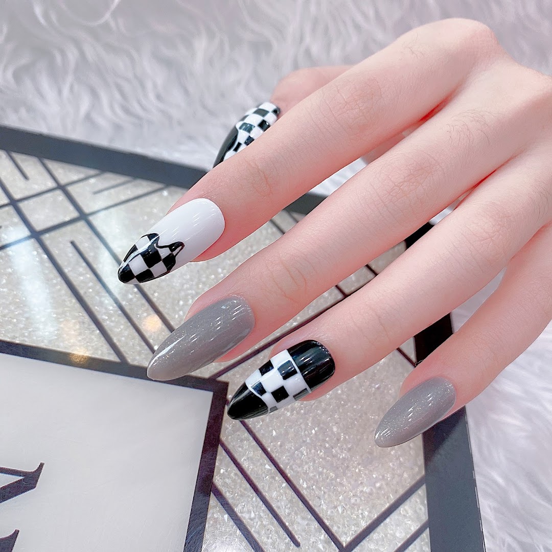 A hand showcasing stylish grey and black-and-white checkered stiletto nails.