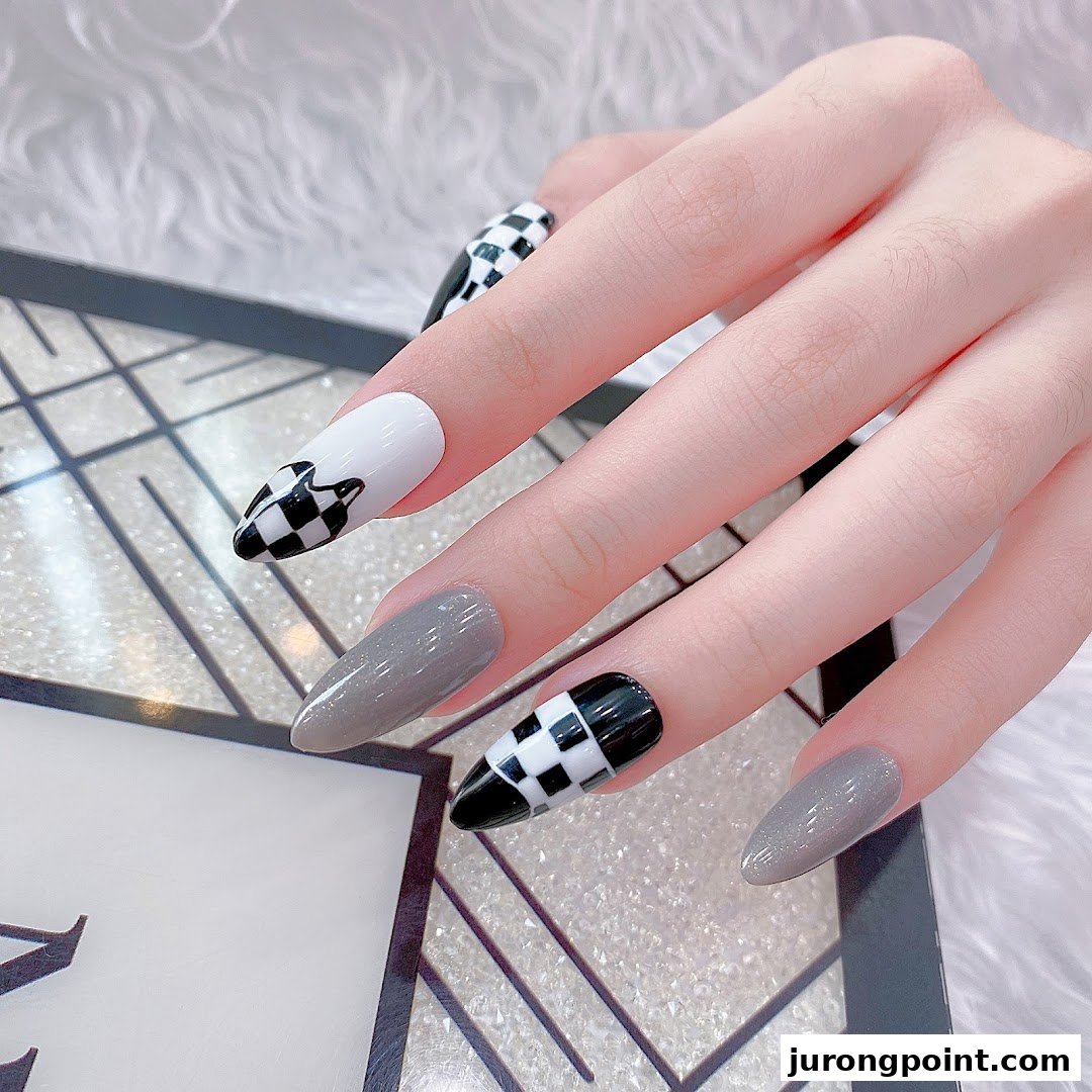 A hand showcasing stylish grey and black-and-white checkered stiletto nails.