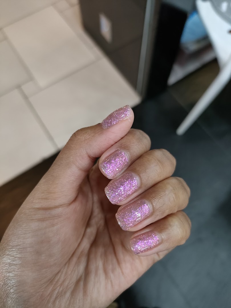 A hand showcasing freshly done nails with sparkling pink glitter polish.
