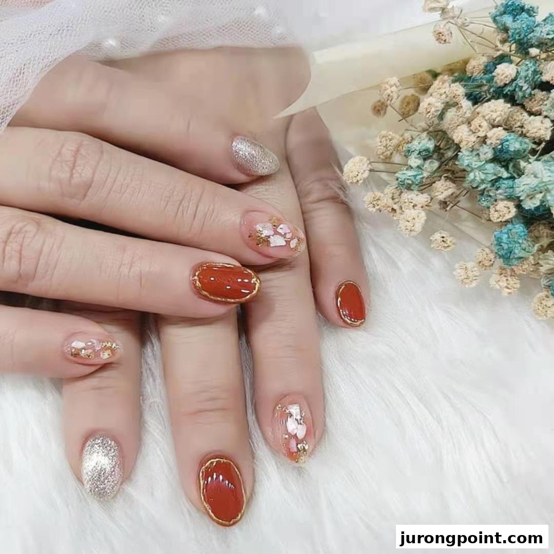 Close-up of hands showcasing intricate nail art with red, gold, and glitter designs.