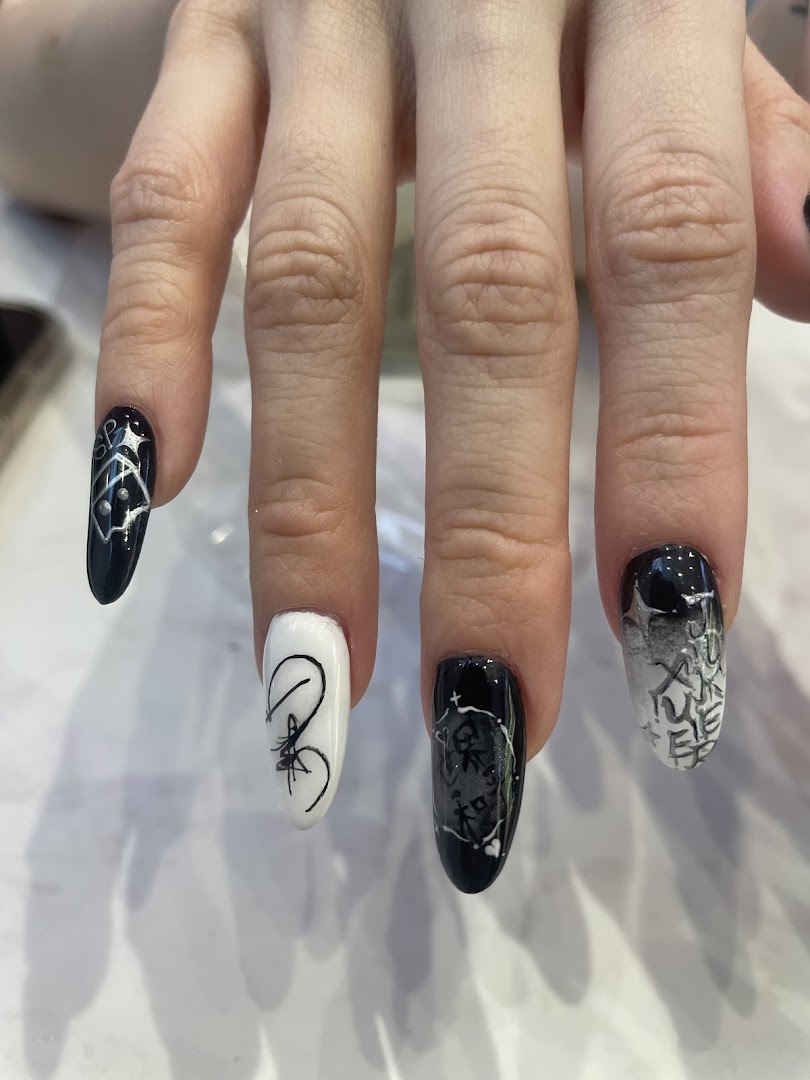 Close-up of a hand showcasing intricate black and white nail art designs.