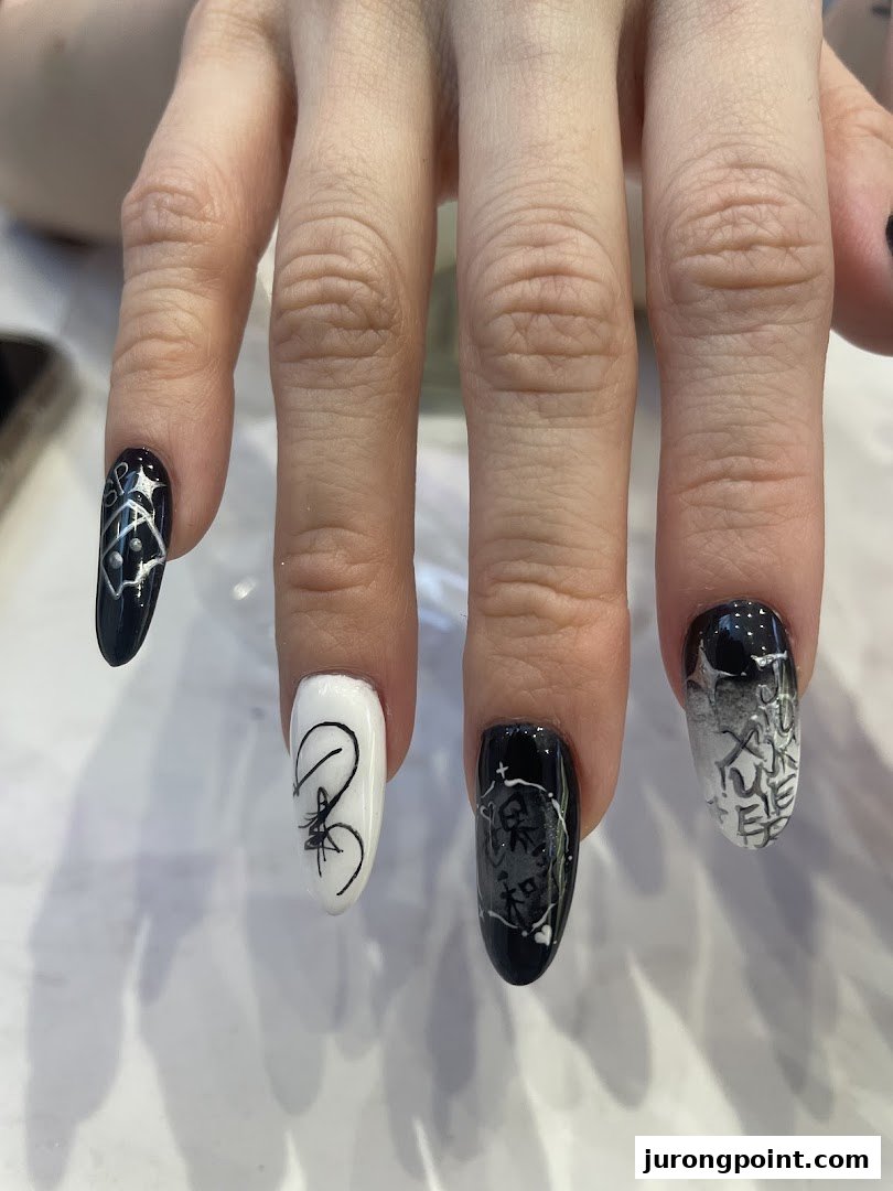 Close-up of a hand showcasing intricate black and white nail art designs.