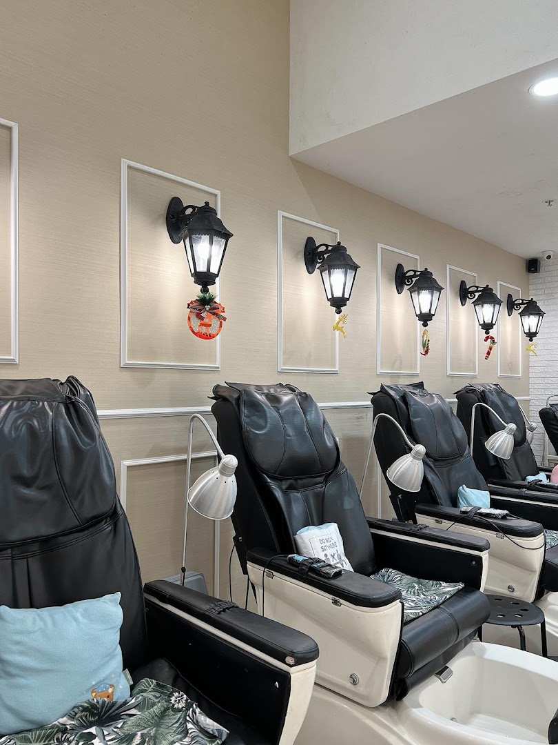 A row of comfortable black pedicure chairs with foot baths and decorative wall lanterns in a modern nail salon.