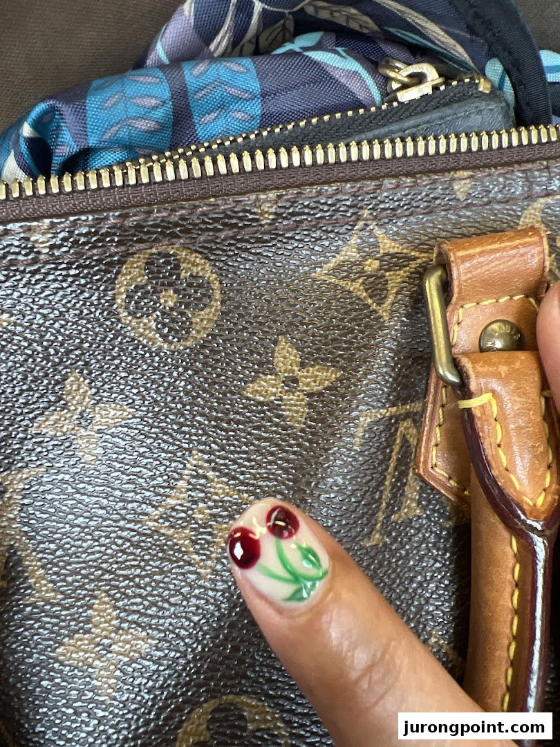 A close-up of a finger showcasing a vibrant cherry-themed nail art design against a textured background.