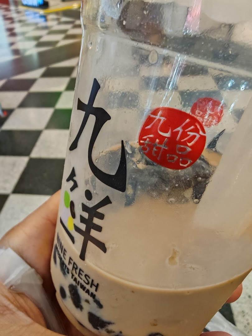 A hand holds a partially consumed bubble tea drink from Nine Fresh Desserts Taiwan, showing the brand logo.