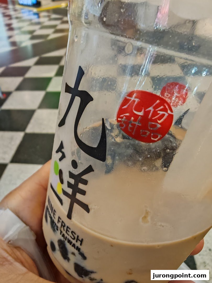 A hand holds a partially consumed bubble tea drink from Nine Fresh Desserts Taiwan, showing the brand logo.