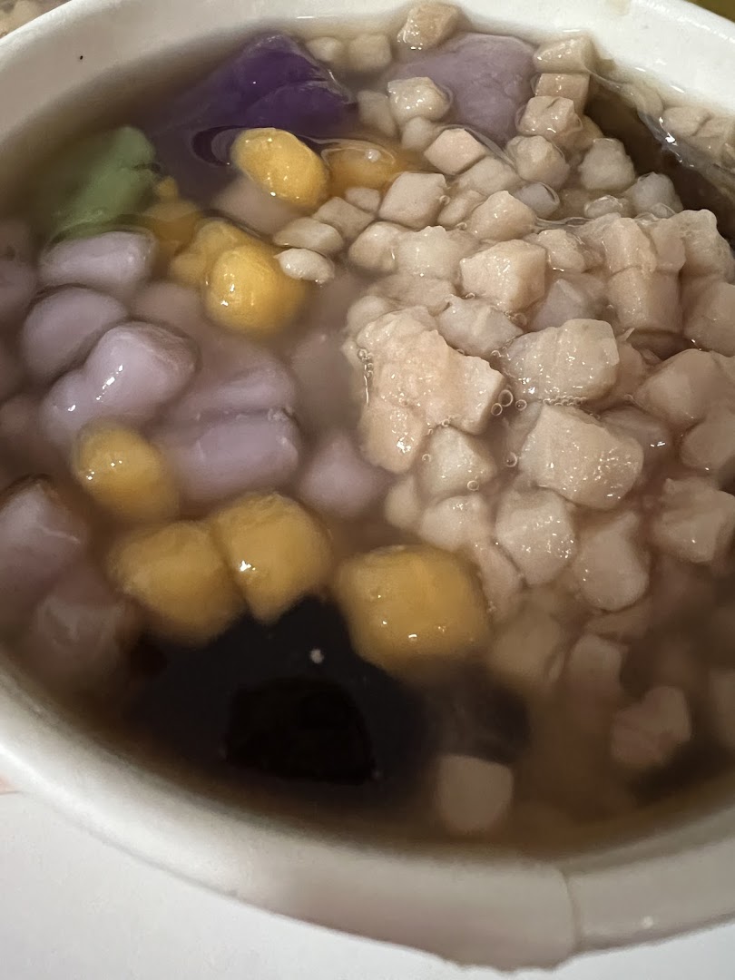 A close-up of a colorful Taiwanese dessert bowl featuring various toppings and a liquid base.