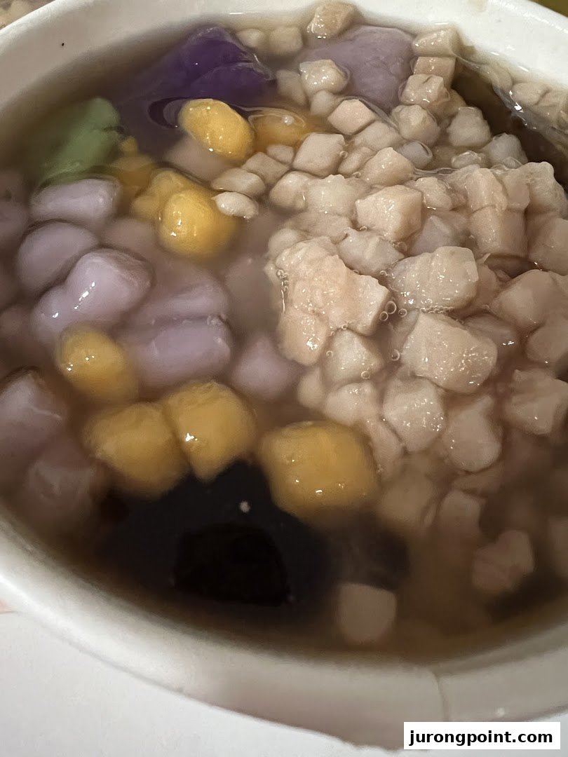 A close-up of a colorful Taiwanese dessert bowl featuring various toppings and a liquid base.