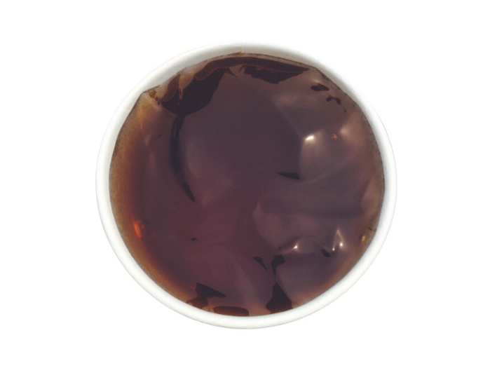 A top-down view of a bowl filled with dark brown grass jelly dessert.