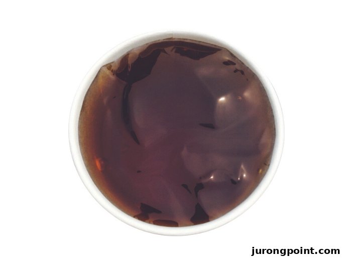 A top-down view of a bowl filled with dark brown grass jelly dessert.