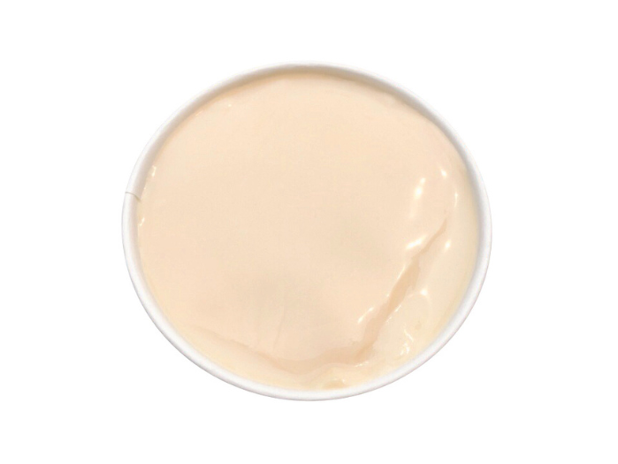 A top-down view of a smooth, light-colored dessert in a white bowl, likely a pudding or panna cotta.