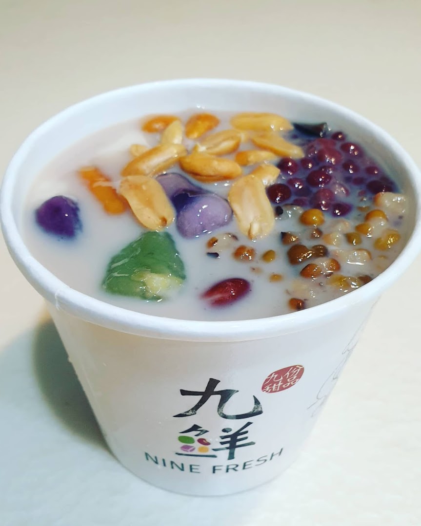 A vibrant cup of Nine Fresh Taiwanese dessert with colorful toppings and a creamy base.