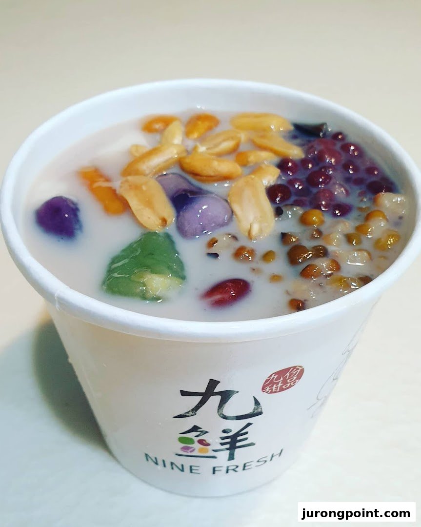 A vibrant cup of Nine Fresh Taiwanese dessert with colorful toppings and a creamy base.
