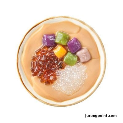 A top-down view of a bowl of Taiwanese dessert with colorful taro balls, grass jelly, and sago.