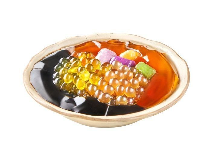 A vibrant bowl of Taiwanese dessert featuring grass jelly, konjac jelly, and popping boba.