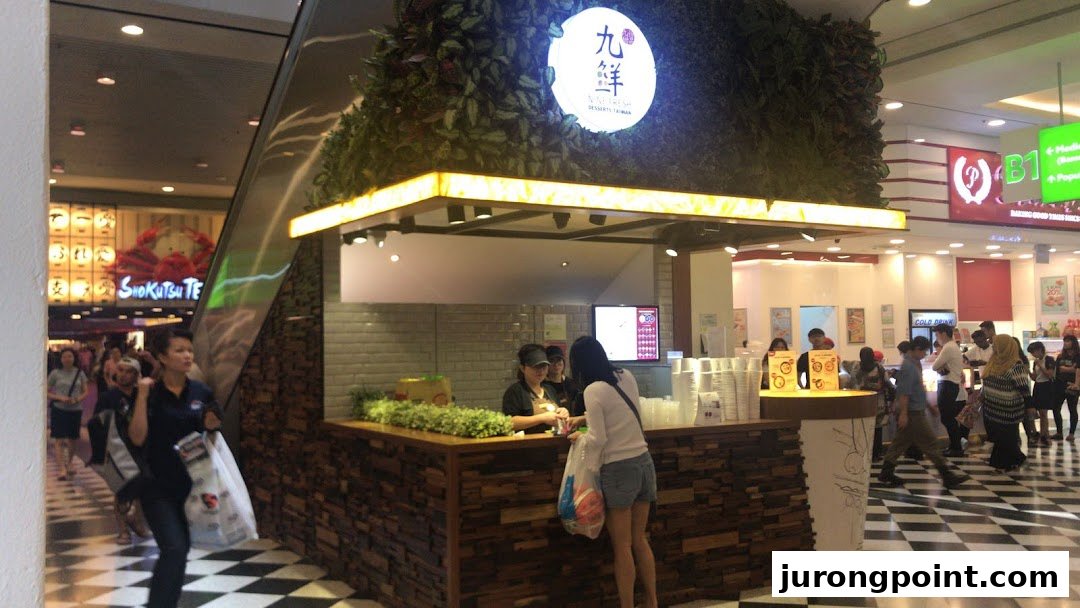 Nine Fresh Desserts Taiwan kiosk in a bustling mall, featuring its distinctive green facade and customers.