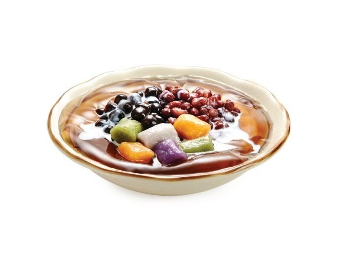 A vibrant bowl of Taiwanese dessert featuring taro balls, red beans, and grass jelly.