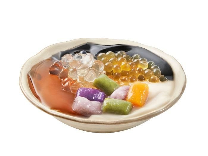 A vibrant bowl of Taiwanese dessert featuring various toppings like taro balls, pearls, and grass jelly.
