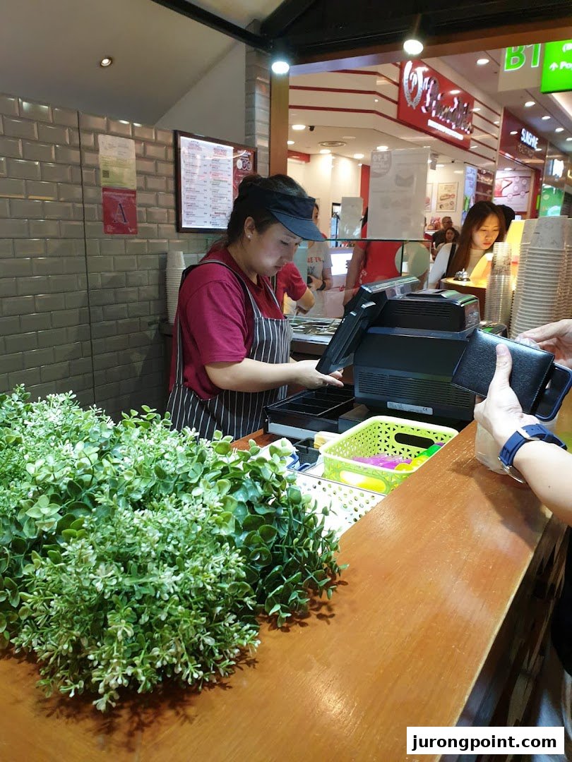 A staff member at Nine Fresh Desserts Taiwan serves a customer at the counter.