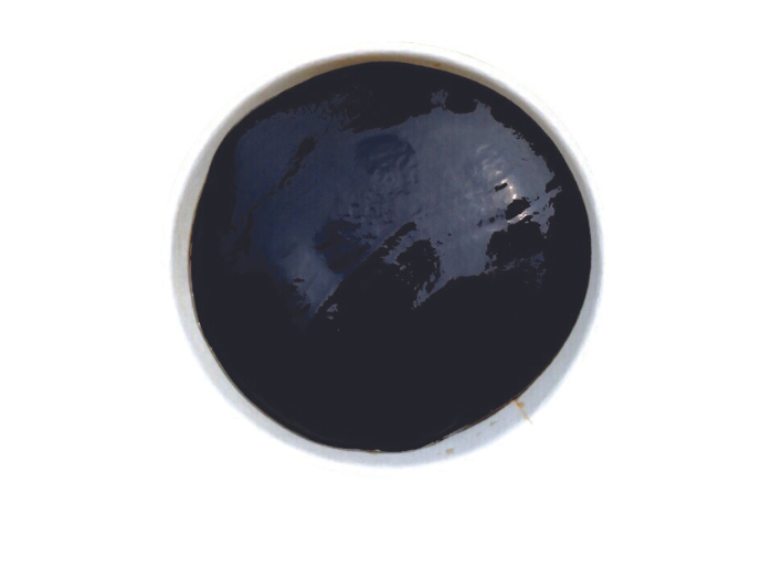 A top-down view of a dark, glossy dessert in a white bowl, likely a jelly or paste.