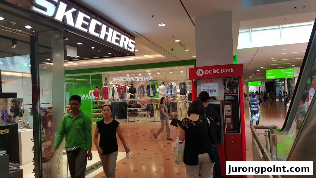 An OCBC ATM machine conveniently located within a bustling shopping mall, near a Skechers store.