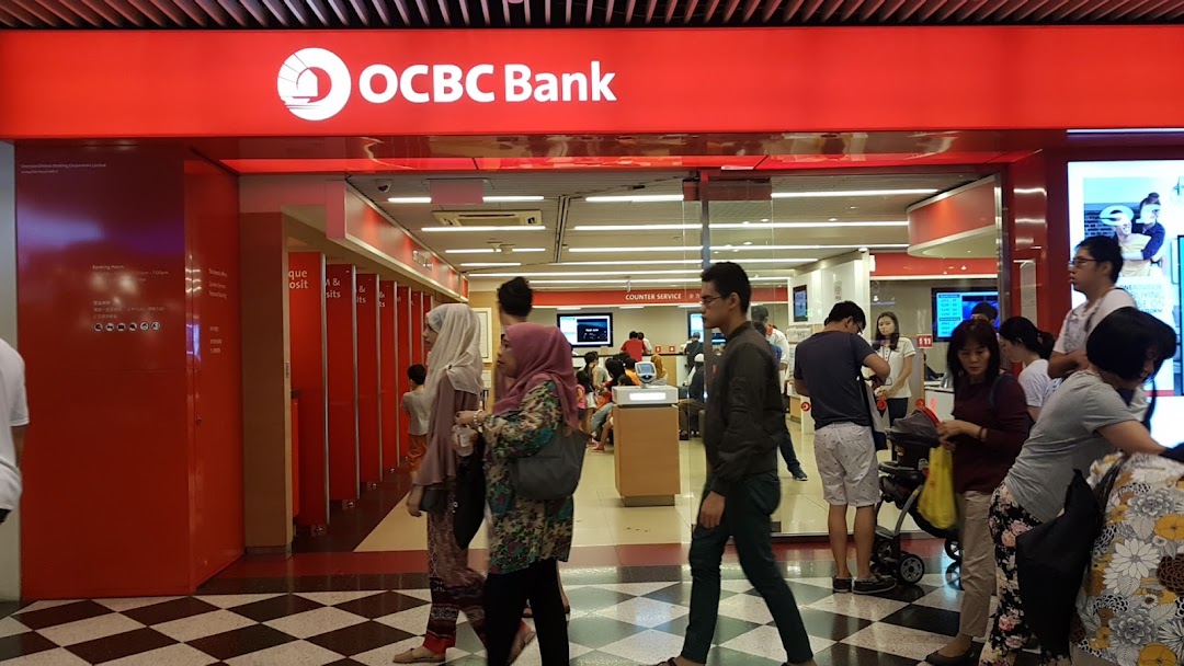 The vibrant red facade of OCBC Bank at Jurong Point, with customers entering and exiting.