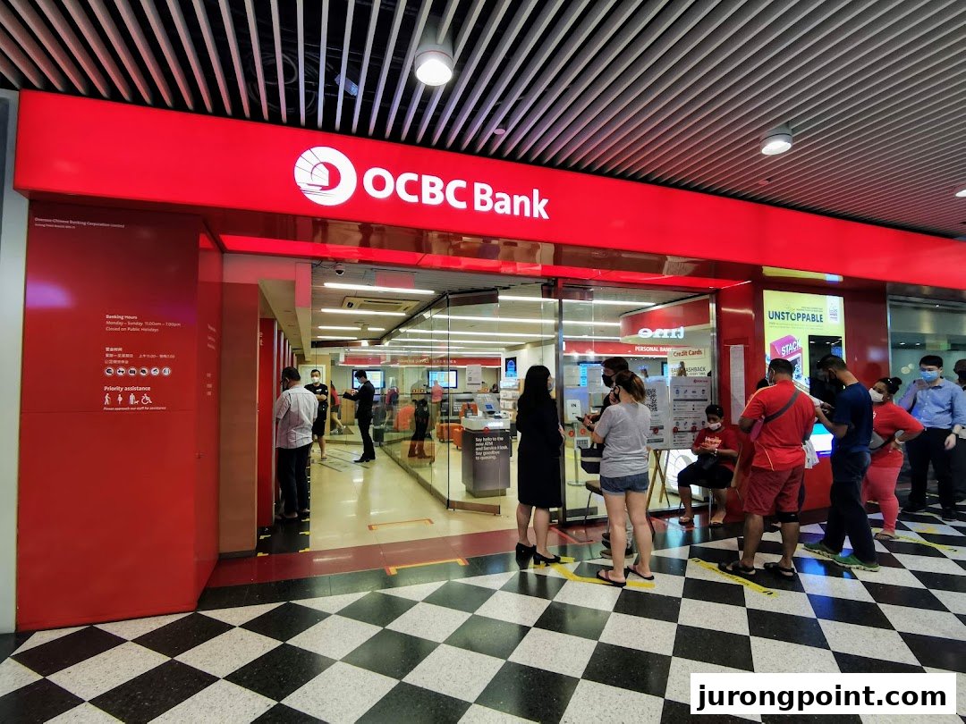 The bright red facade of OCBC Bank at Jurong Point, with customers entering and queuing.