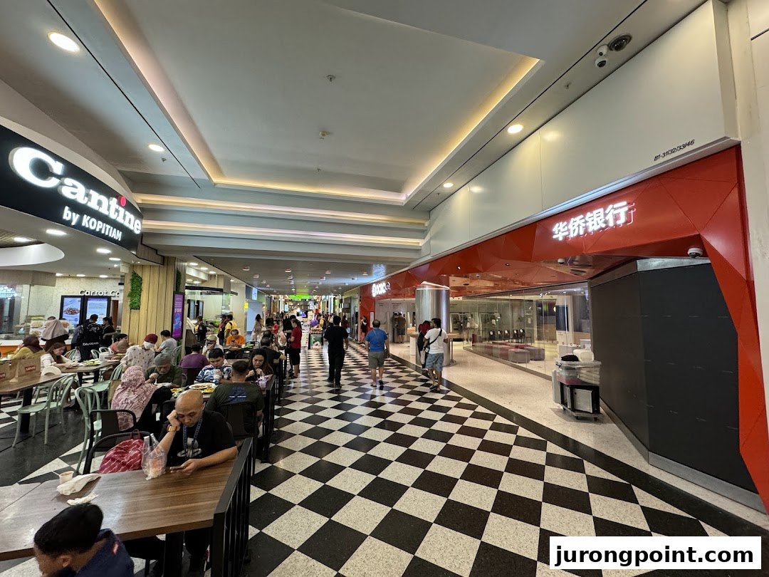 The entrance of OCBC Bank with its distinctive red facade, located next to a bustling food court.