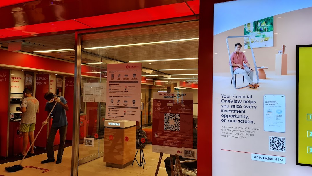 The entrance of OCBC Bank with ATMs, staff cleaning, and a digital financial services advertisement.