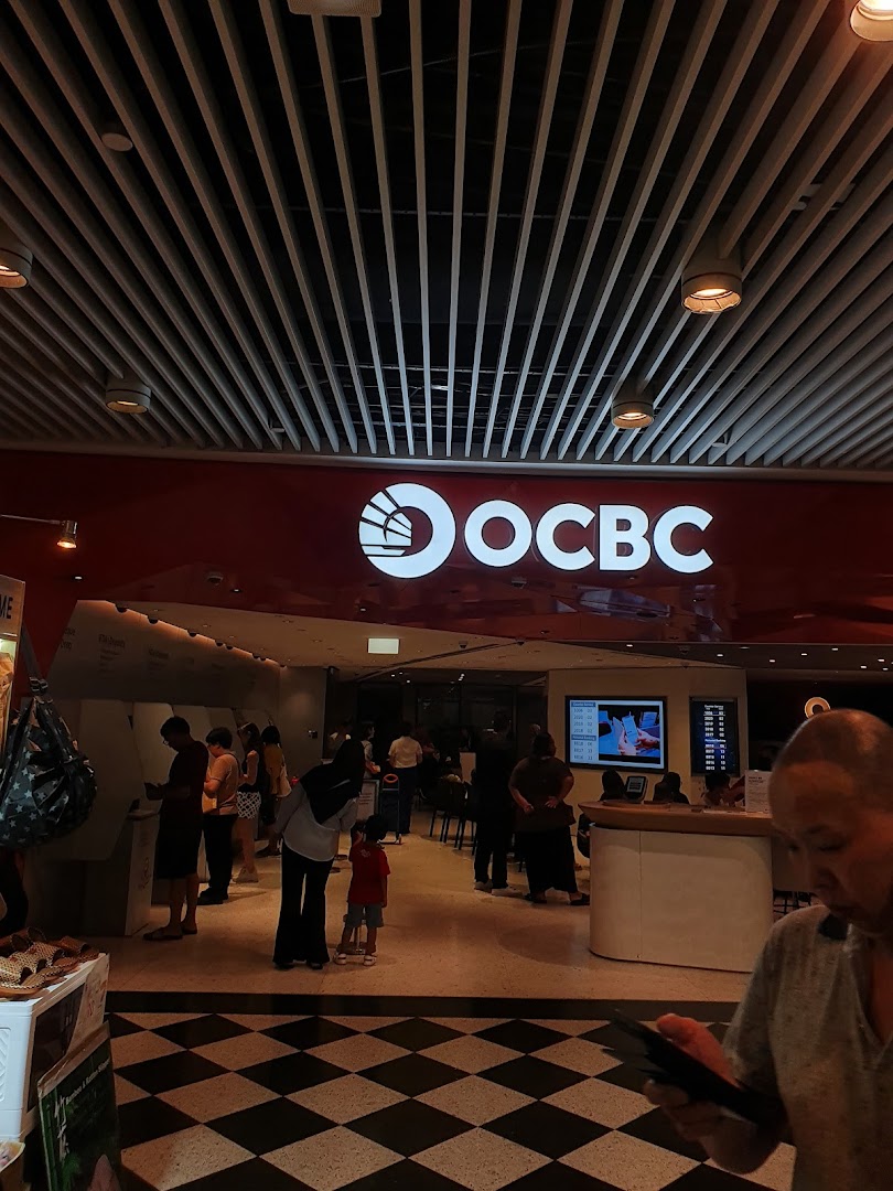 The OCBC Bank branch entrance with customers inside, featuring the prominent bank logo.