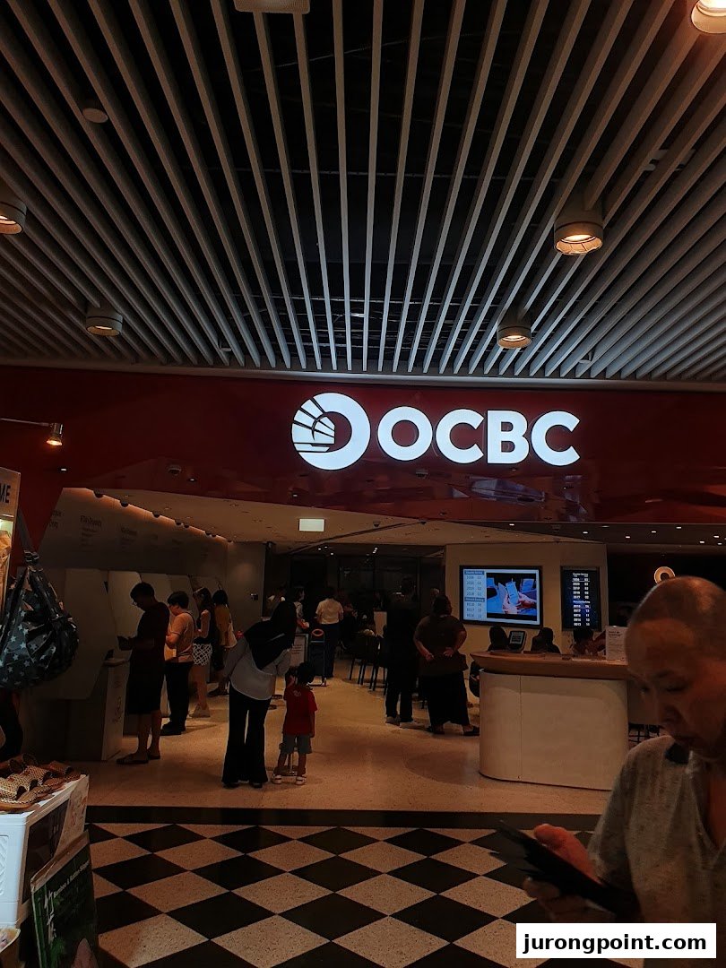 The OCBC Bank branch entrance with customers inside, featuring the prominent bank logo.