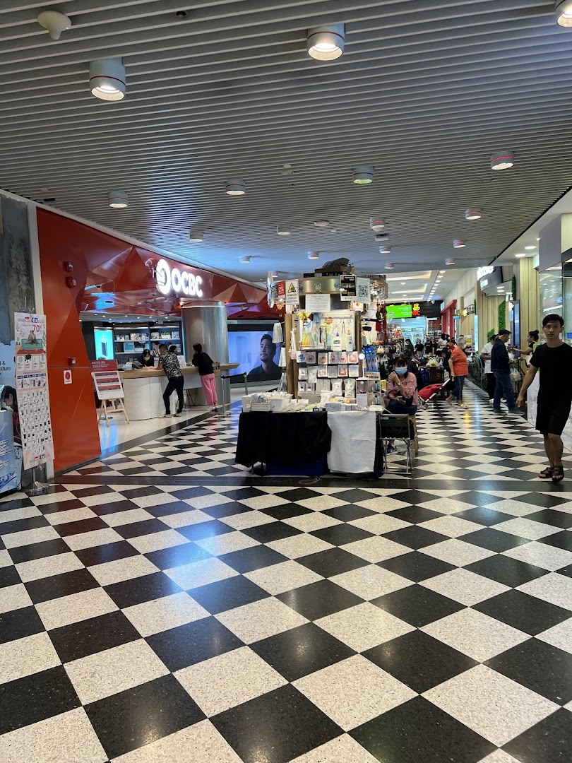 The OCBC Bank branch entrance at Jurong Point, featuring a distinctive checkered floor and mall activity.
